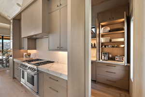 Kitchen featuring range with two ovens, light wood-style floors, and light stone countertops
