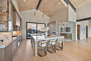 Kitchen featuring a kitchen bar, light stone counters, light wood-type flooring, modern cabinets, and a spacious island