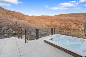 View of patio with a mountain view and a hot tub