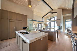 Kitchen featuring light wood-style flooring, stainless steel stove, a high wooden beamed ceiling, paneled refrigerator, and light stone counters