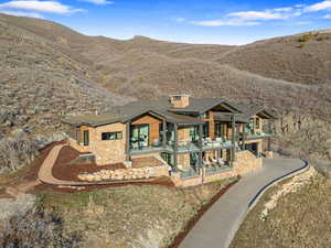 Back of property with a balcony, driveway, a mountain view, a patio, and a garage