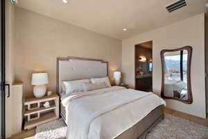 Bedroom featuring light wood-style floors, ensuite bath, recessed lighting, and a mountain view