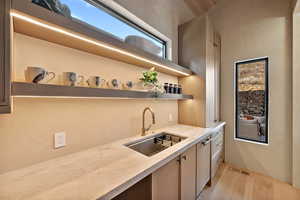 Kitchen with light stone countertops, open shelves, and light wood-style flooring