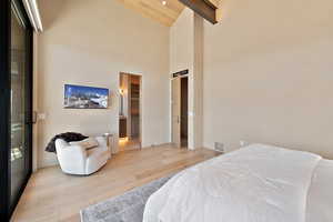 Bedroom featuring light wood-type flooring, a high wooden beamed ceiling, and connected bathroom