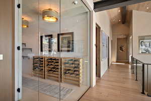Wine cellar featuring light wood-style floors, a high wood beamed ceiling, and recessed lighting