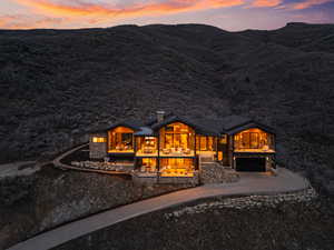 View of front facade with a chimney, a garage, concrete driveway, and stone siding