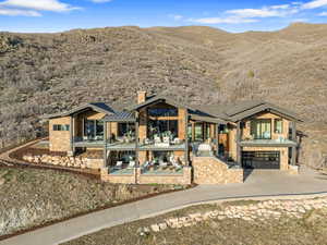 Back of property featuring a patio area, driveway, an attached garage, a mountain view, and brick siding