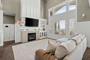 Living area with a decorative wall, wainscoting, a high ceiling, and a fireplace