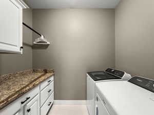 Laundry area with a textured ceiling, washer and clothes dryer, and cabinet space