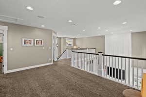 Hallway featuring an upstairs landing, dark carpet, and recessed lighting