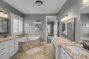 Full bath featuring a bath, two vanities, and connected bathroom