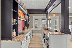 Kitchen featuring open shelves, light stone counters, light wood-type flooring, and ornamental molding
