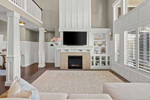 Living room with a decorative wall, a wainscoted wall, dark wood finished floors, a fireplace, and a high ceiling