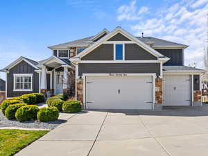 Craftsman inspired home featuring board and batten siding, driveway, stone siding, and a garage