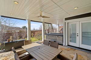 Fenced backyard with a hot tub, outdoor dining area, a patio area, and a ceiling fan