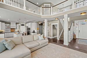 Living room with dark wood-style floors, a high ceiling, decorative columns, and recessed lighting