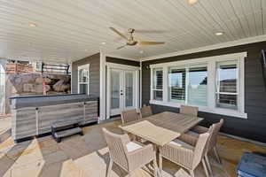 View of patio with outdoor dining space, a hot tub, ceiling fan, and french doors