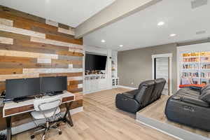 Office space featuring built in shelves, light wood-style floors, and recessed lighting