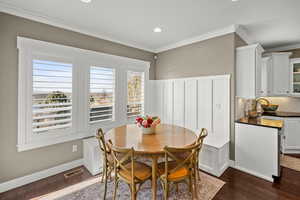 Dining area with ornamental molding, dark wood finished floors, and recessed lighting