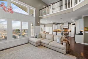 Living room featuring a high ceiling, dark wood-type flooring, plenty of natural light, recessed lighting, and a decorative wall