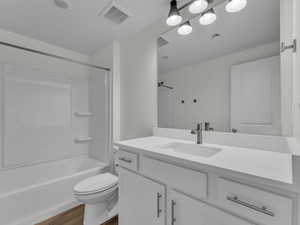 Bathroom featuring vanity, shower / bathtub combination, and dark wood-style floors