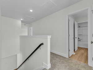 Corridor featuring an upstairs landing, light colored carpet, and recessed lighting