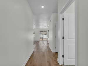 Hall with light wood-type flooring and recessed lighting