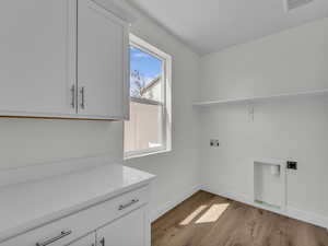 Laundry room featuring washer hookup, light wood-style floors, and cabinet space