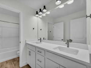 Full bathroom with double vanity, light wood finished floors, and tub / shower combination