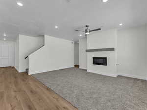 Unfurnished living room featuring a glass covered fireplace, ceiling fan, recessed lighting, a textured ceiling, and light wood-style floors