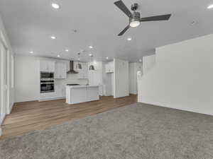Unfurnished living room with recessed lighting, a ceiling fan, dark colored carpet, and dark wood-style floors