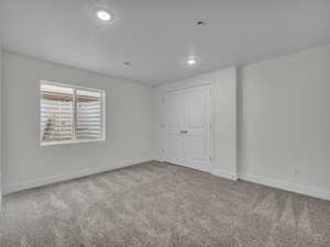 Unfurnished bedroom with light carpet, a closet, and recessed lighting