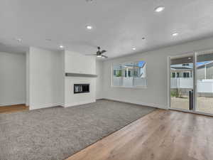 Unfurnished living room with light wood-style flooring, recessed lighting, a textured ceiling, a glass covered fireplace, and a ceiling fan