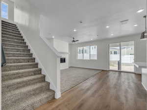 Stairway featuring a textured ceiling, wood finished floors, a glass covered fireplace, recessed lighting, and a ceiling fan