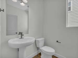 Half bathroom with toilet and wood finished floors