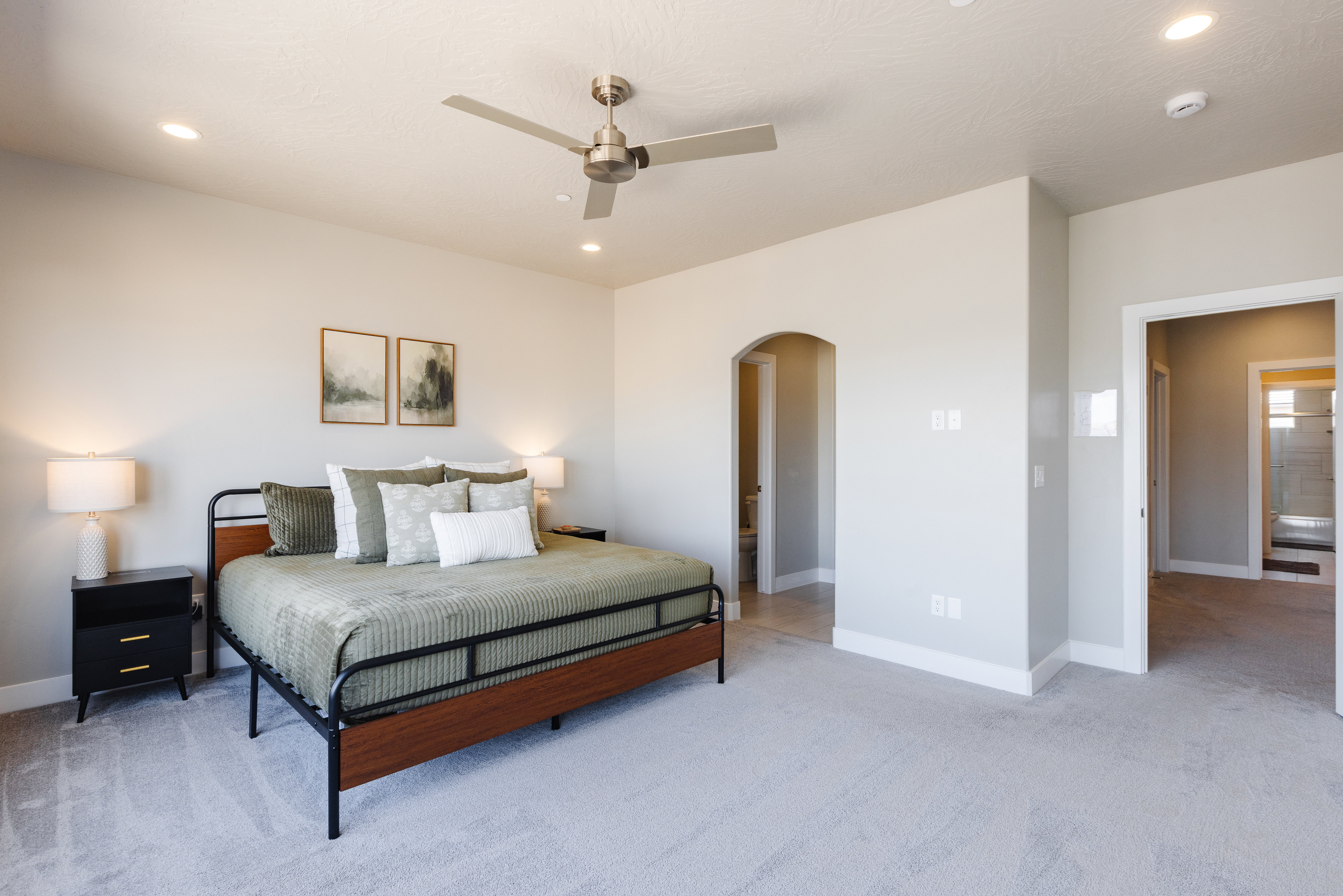 Bedroom with light carpet, arched walkways, a ceiling fan, and recessed lighting