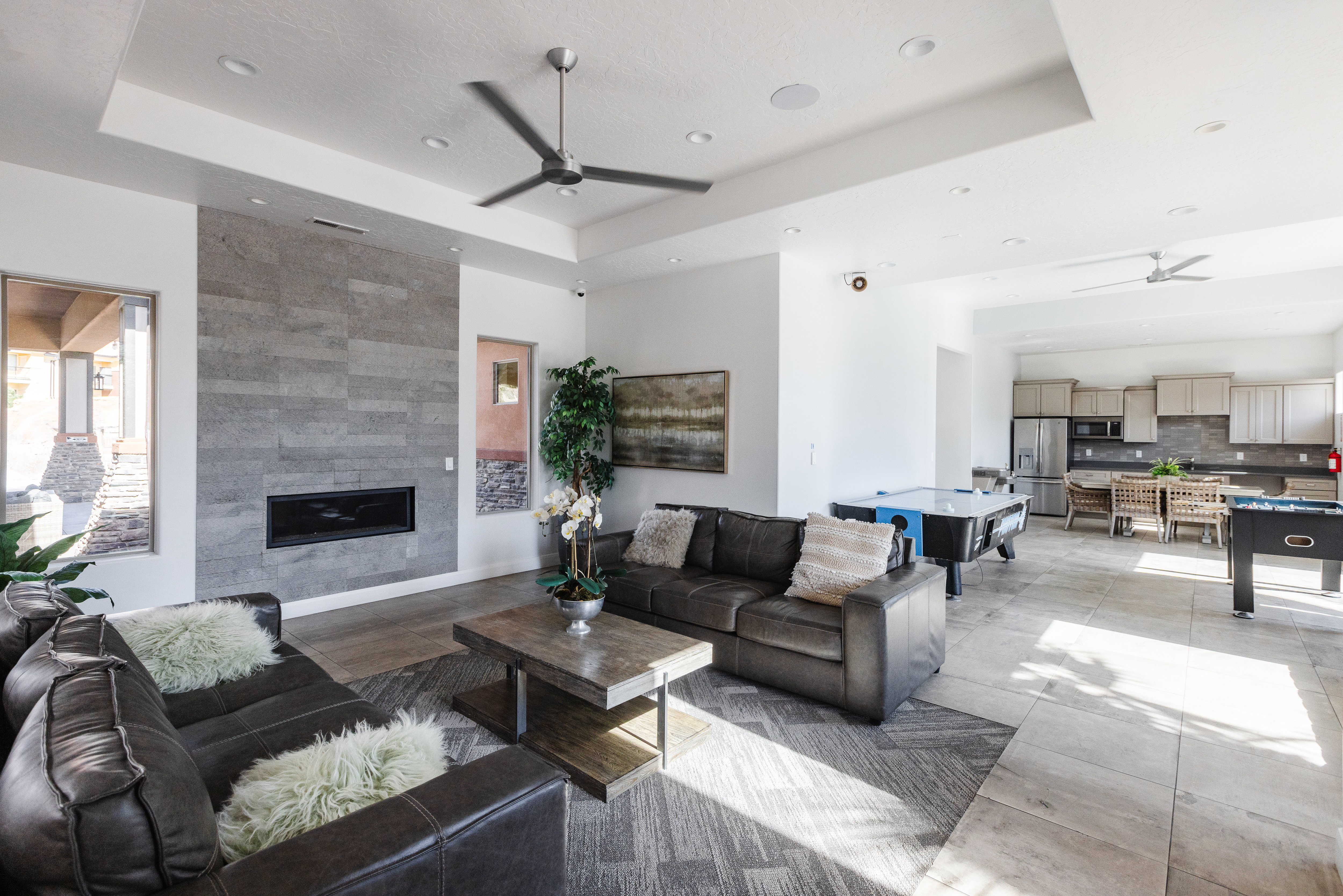 Living area with ceiling fan, a tile fireplace, and a raised ceiling