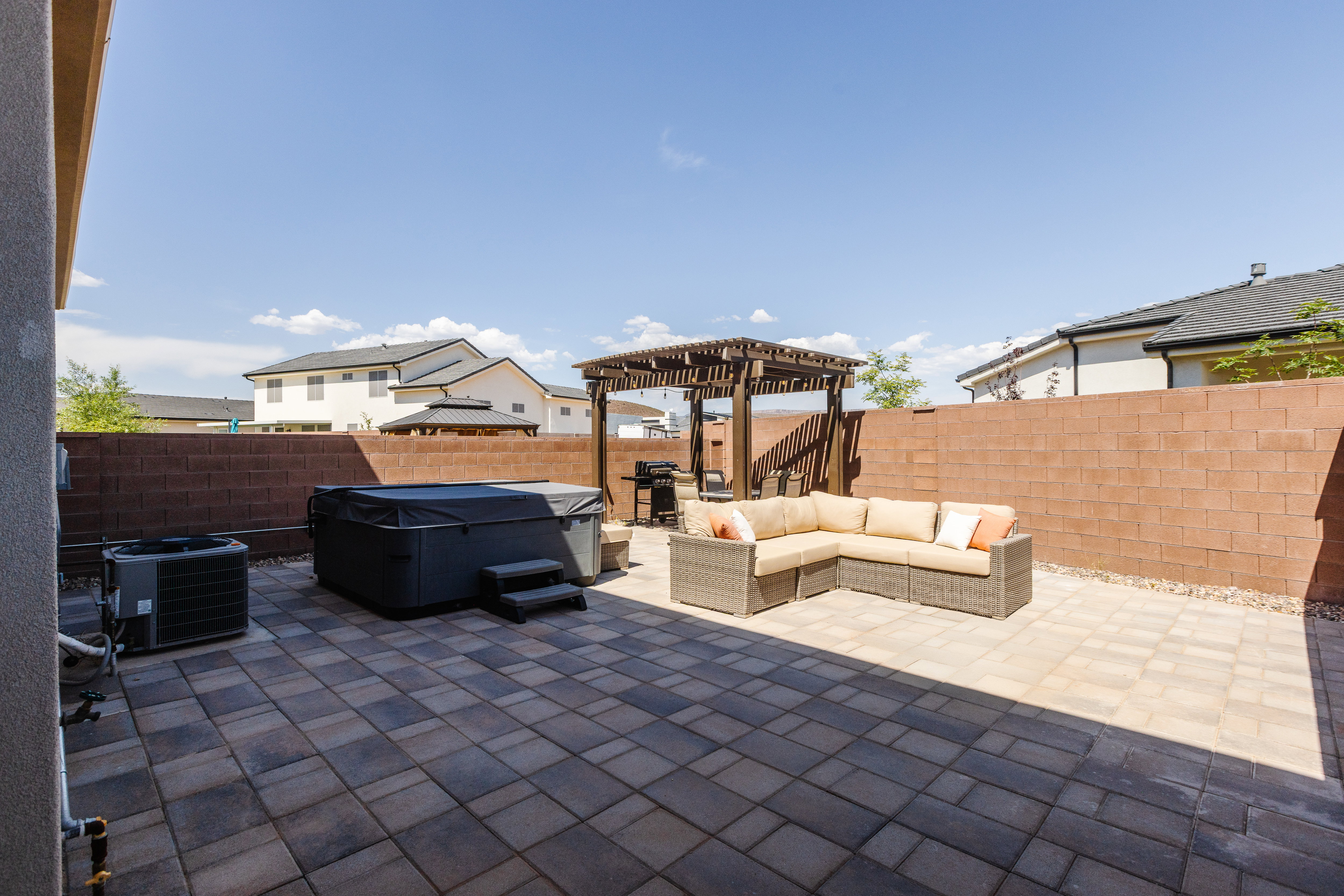 Fenced backyard with an outdoor lounge area, a patio area, area for grilling, a pergola, and a hot tub