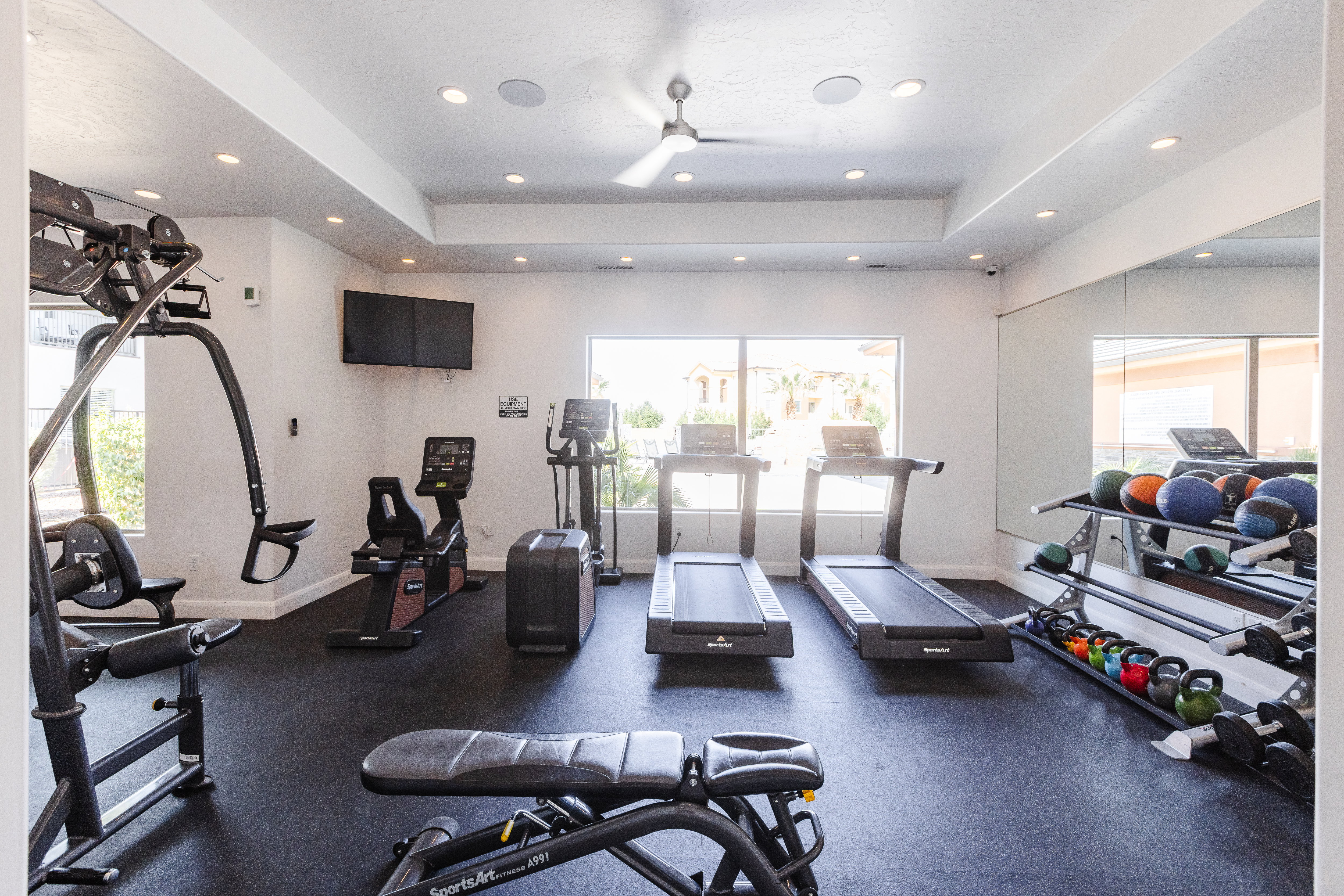 Exercise room featuring a tray ceiling, a ceiling fan, and recessed lighting