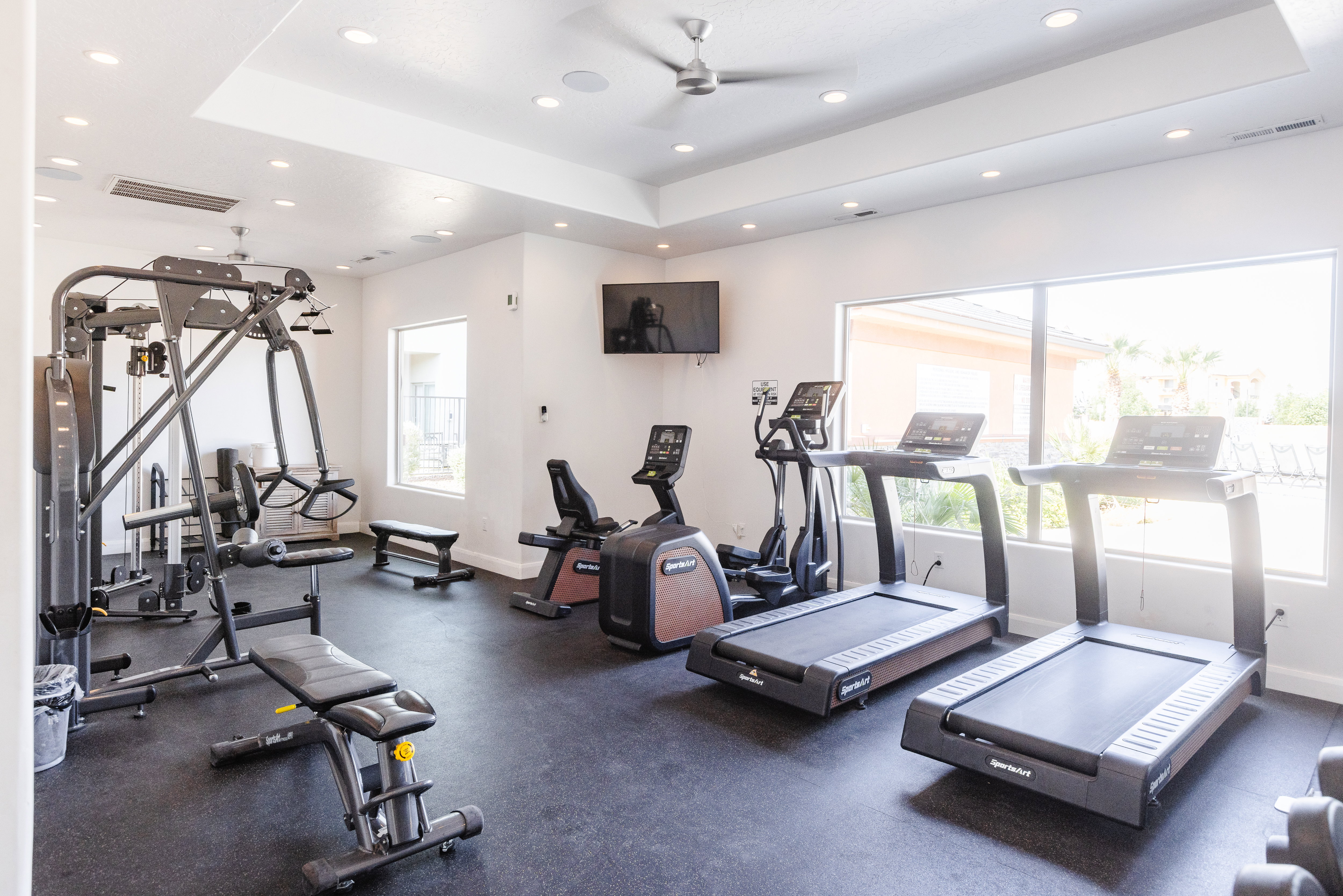 Gym featuring a tray ceiling, ceiling fan, and recessed lighting