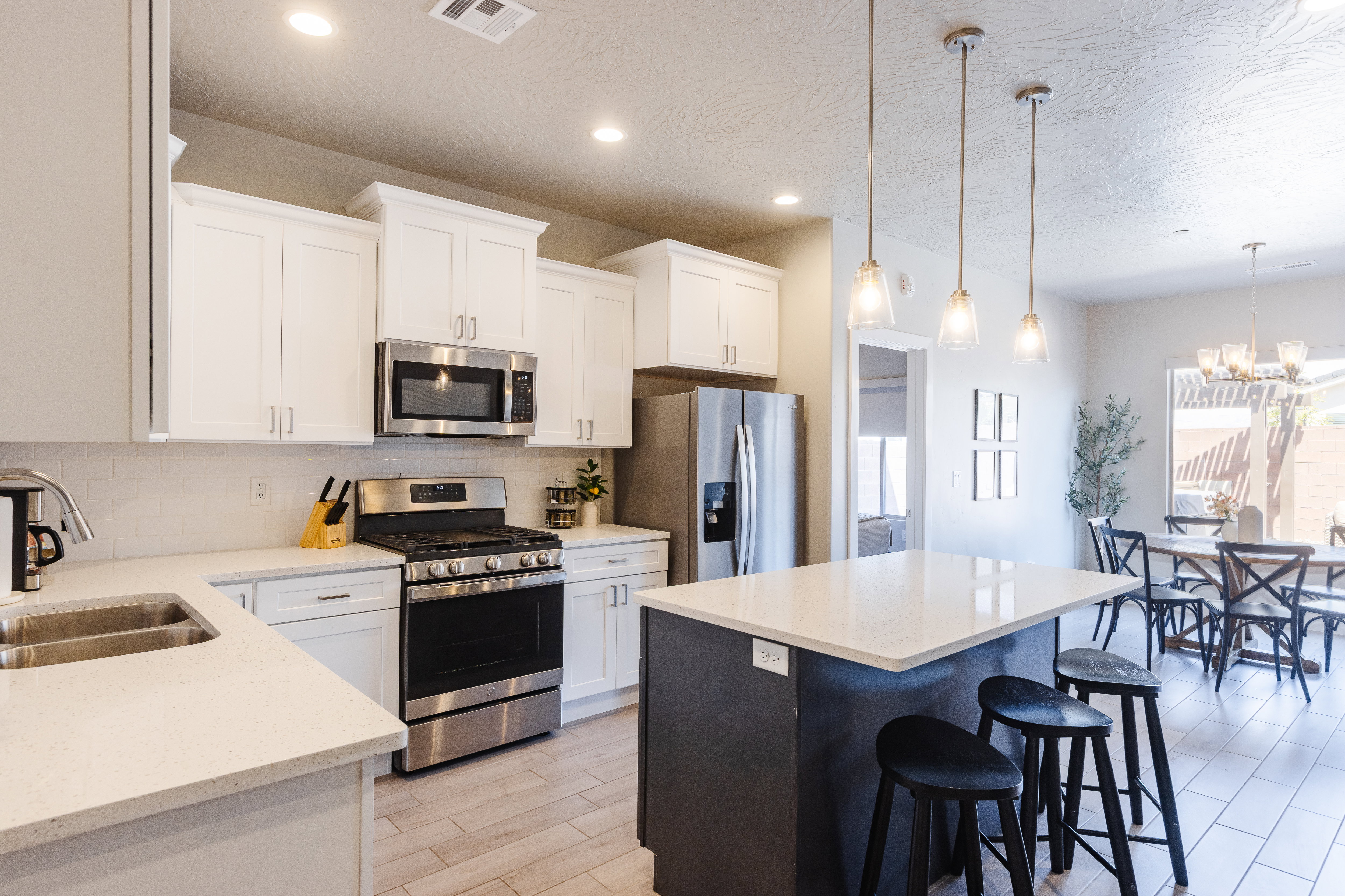 Dual tone kitchen featuring stainless steel appliances, a kitchen island, tasteful backsplash, wood finish floors, and light stone counters