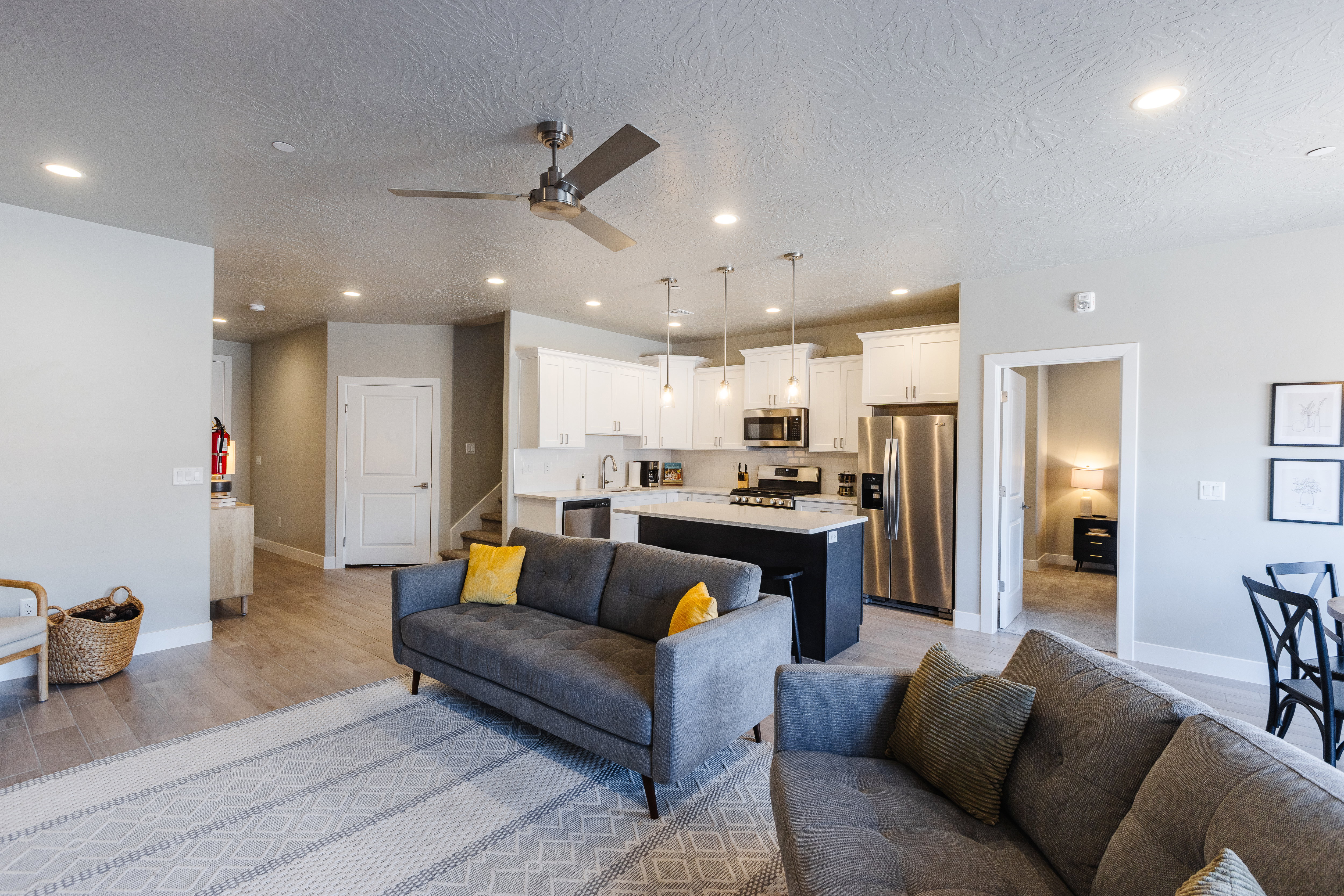 Living area with light wood finished floors, ceiling fan, a textured ceiling, and recessed lighting