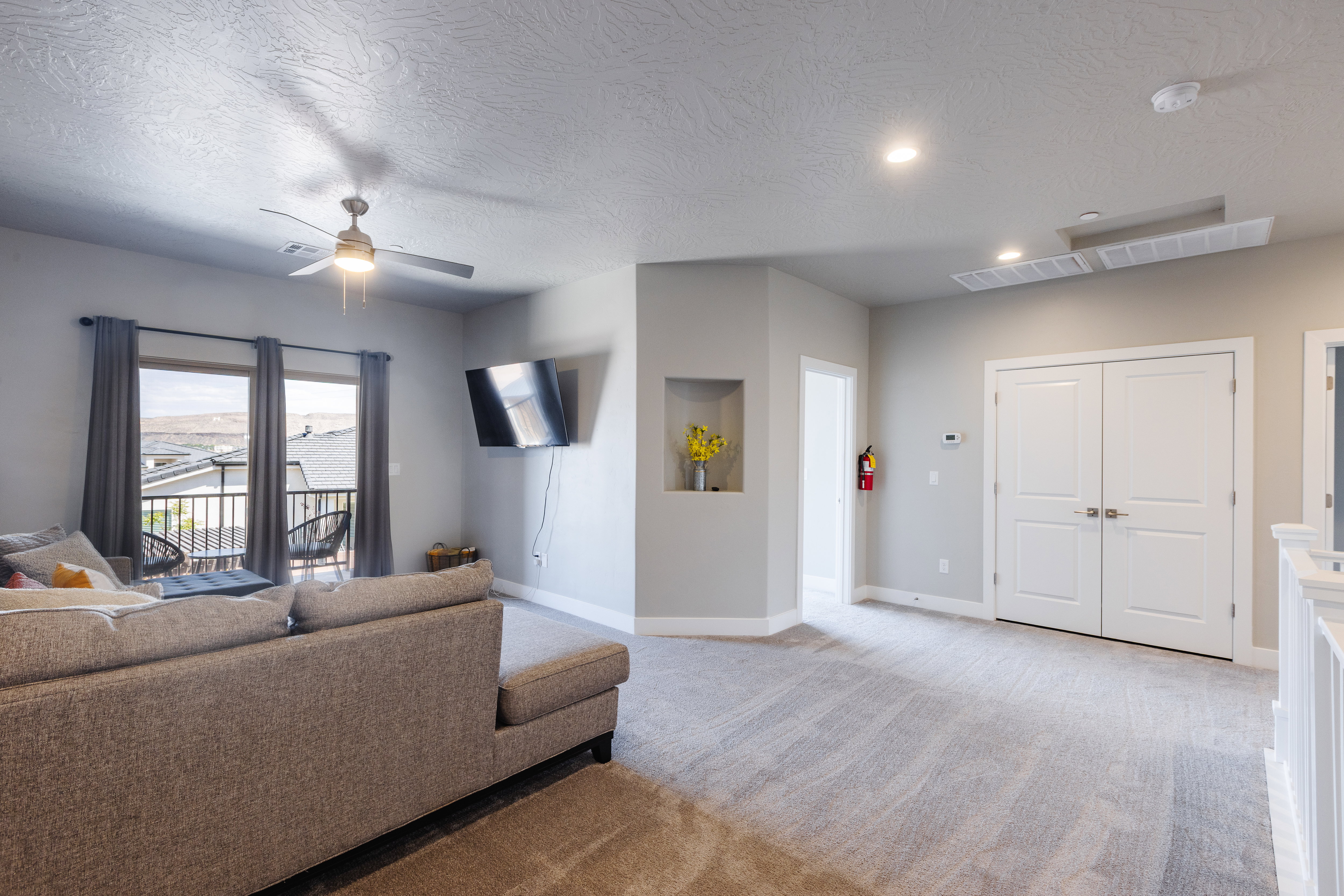 Carpeted living area featuring ceiling fan and a textured ceiling