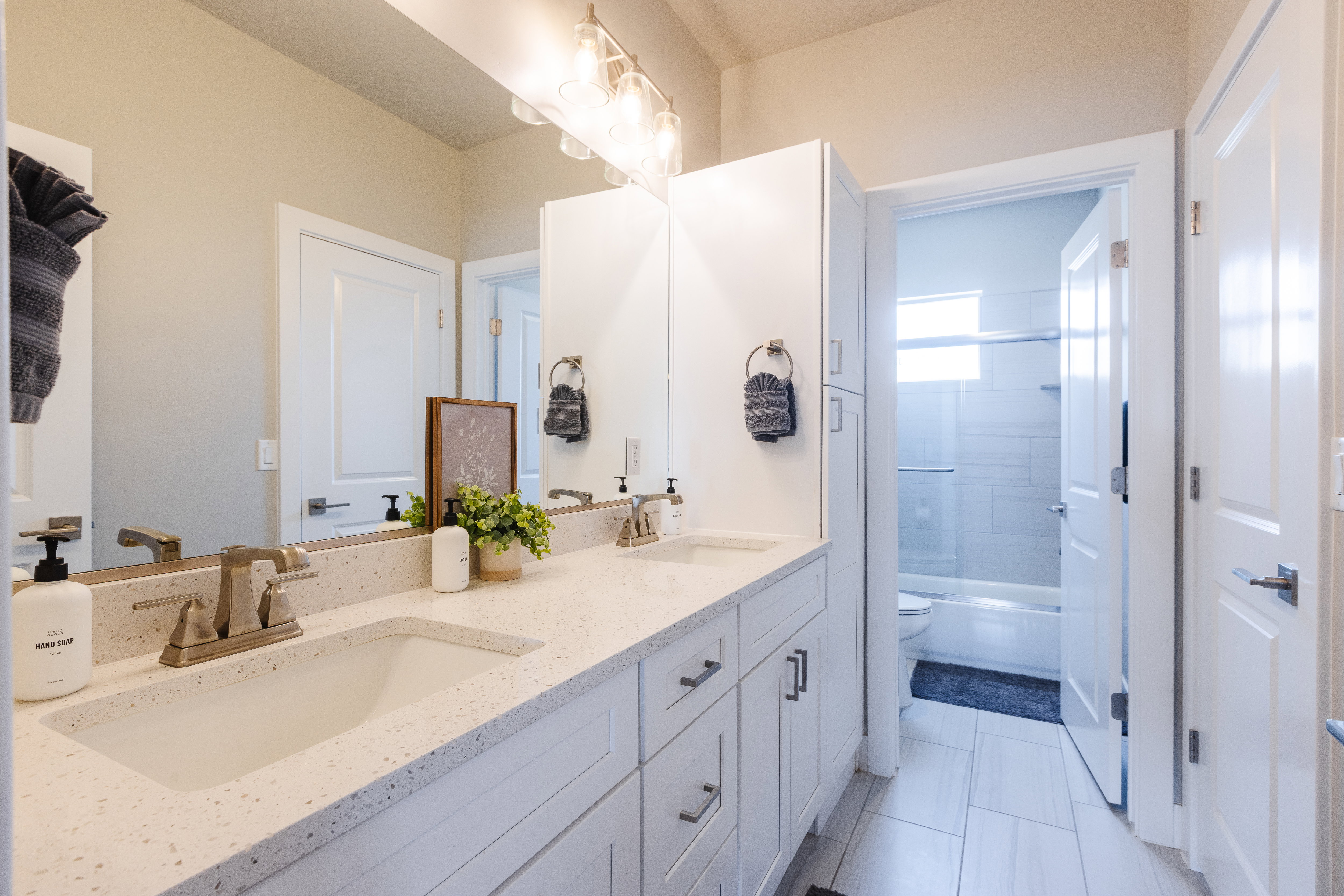 Full bath with double vanity and bath / shower combo with glass door