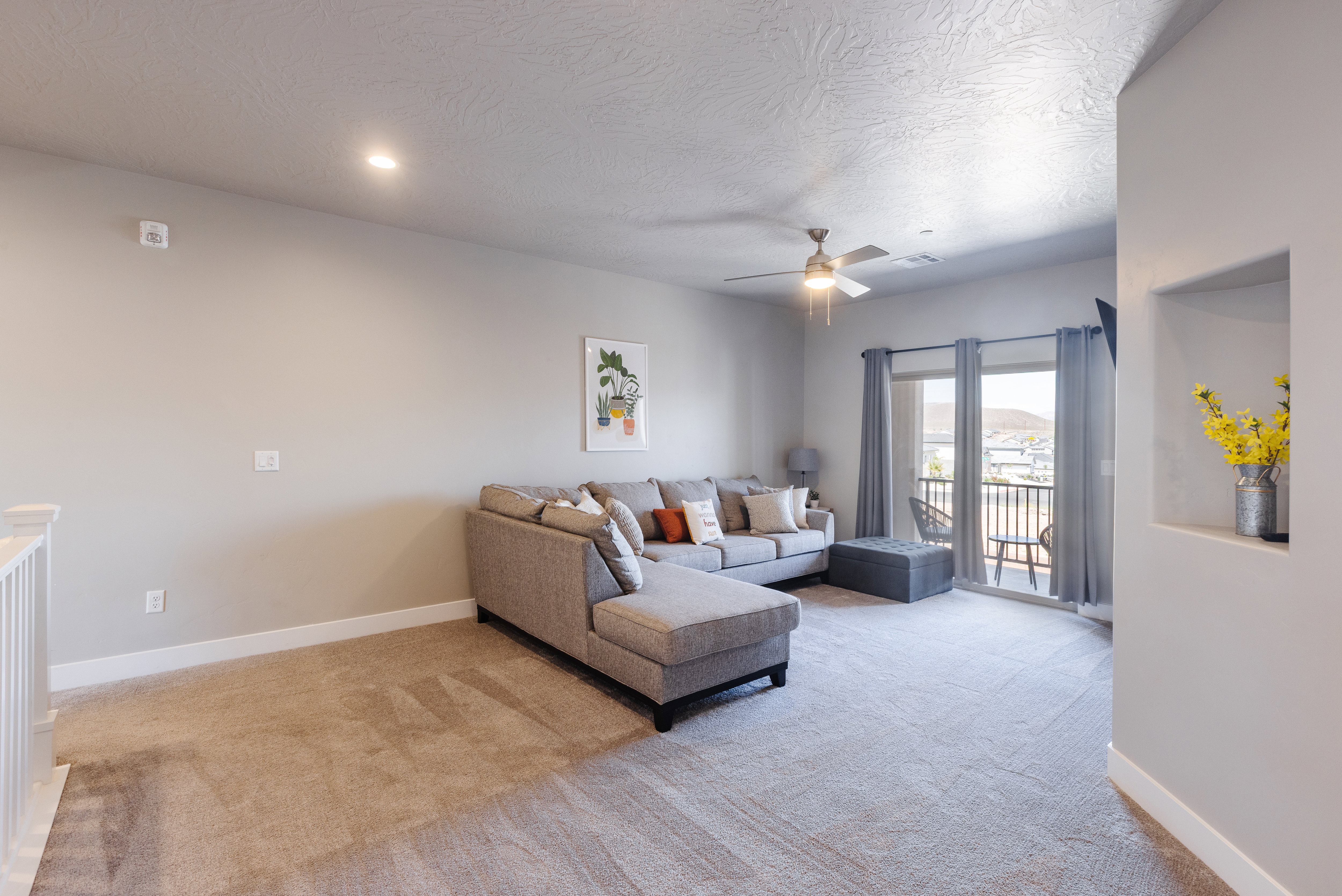 Living room featuring light carpet, a ceiling fan, and a textured ceiling