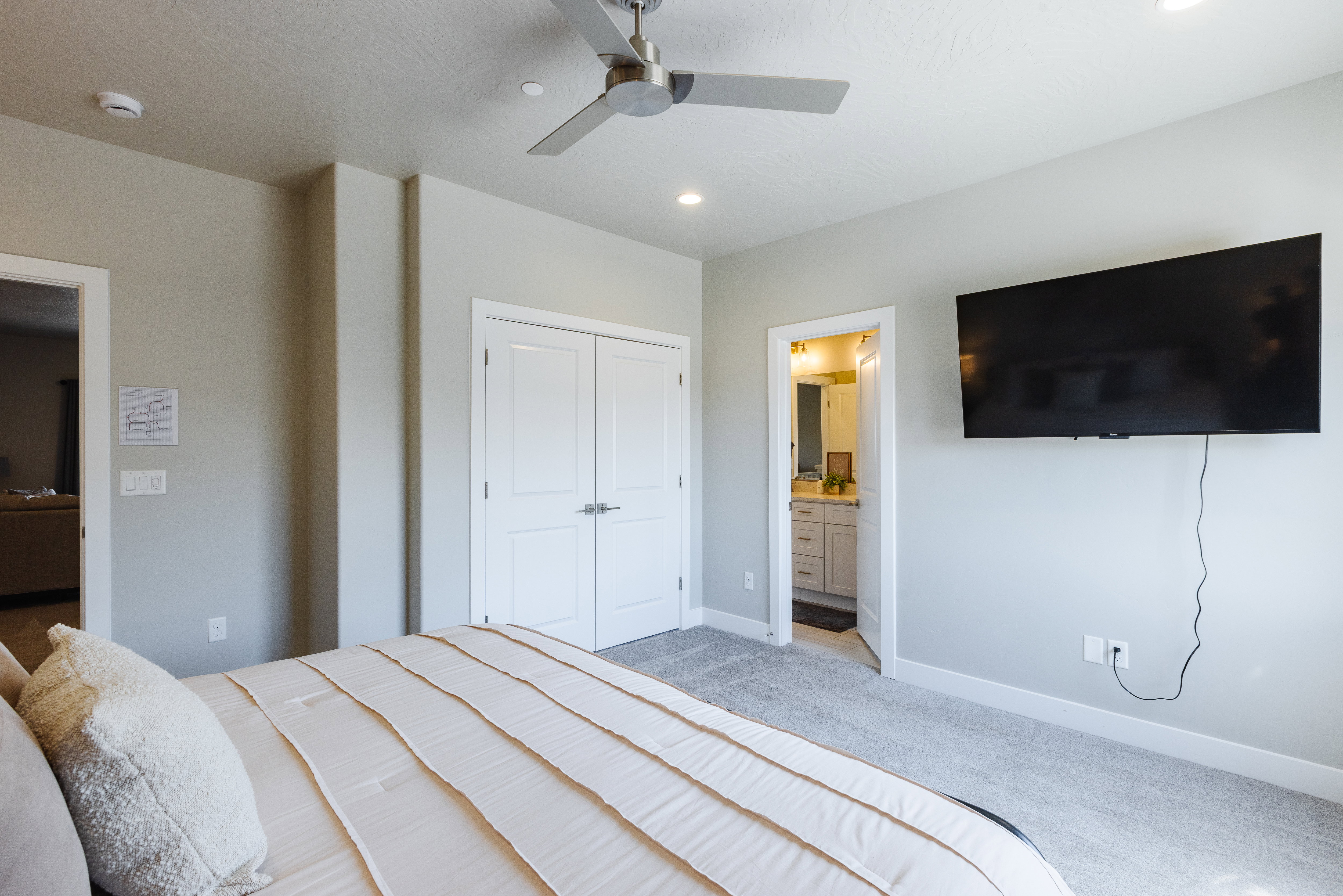 Bedroom featuring light colored carpet, ensuite bath, ceiling fan, and a closet