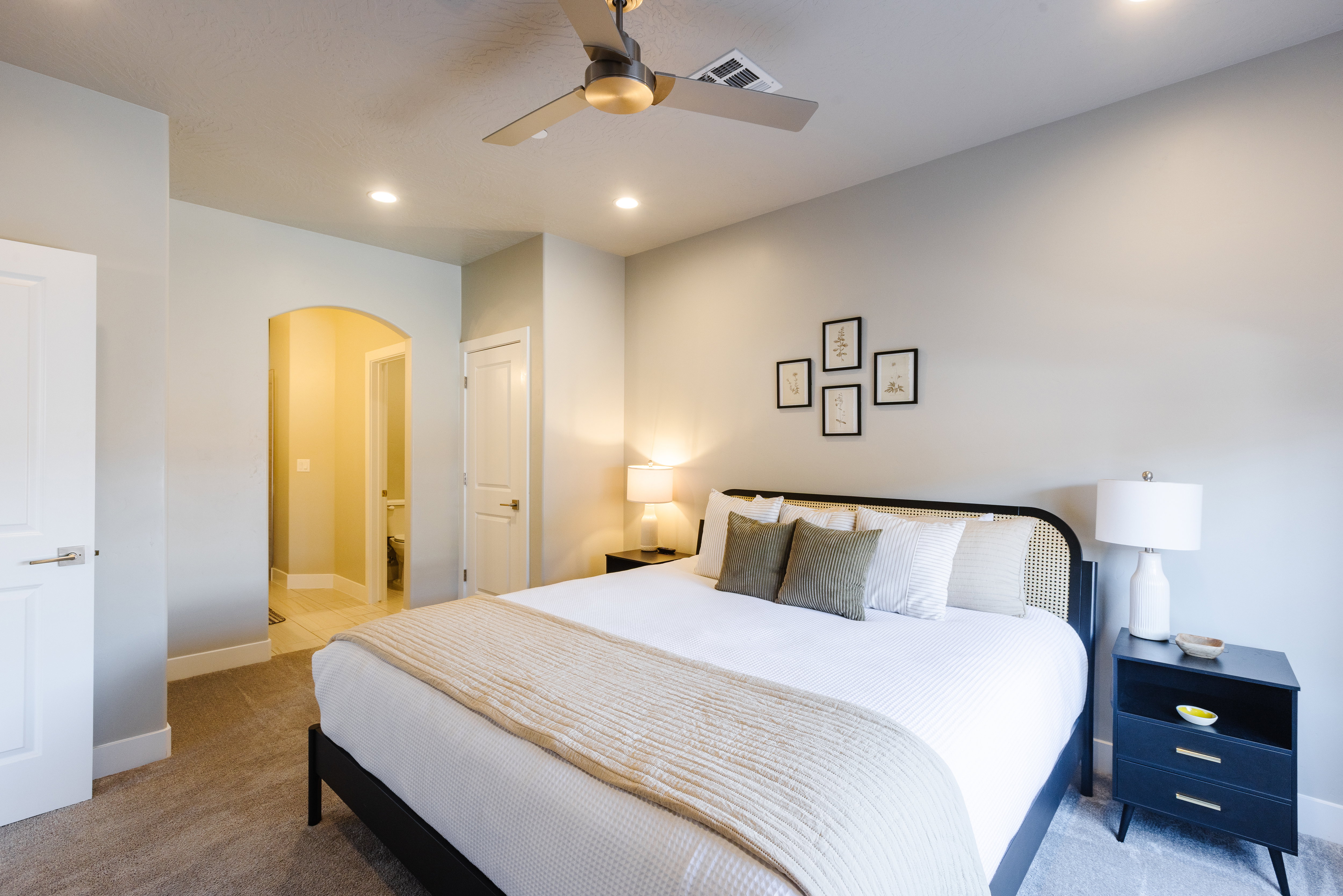 Bedroom with arched walkways, light carpet, ceiling fan, and recessed lighting