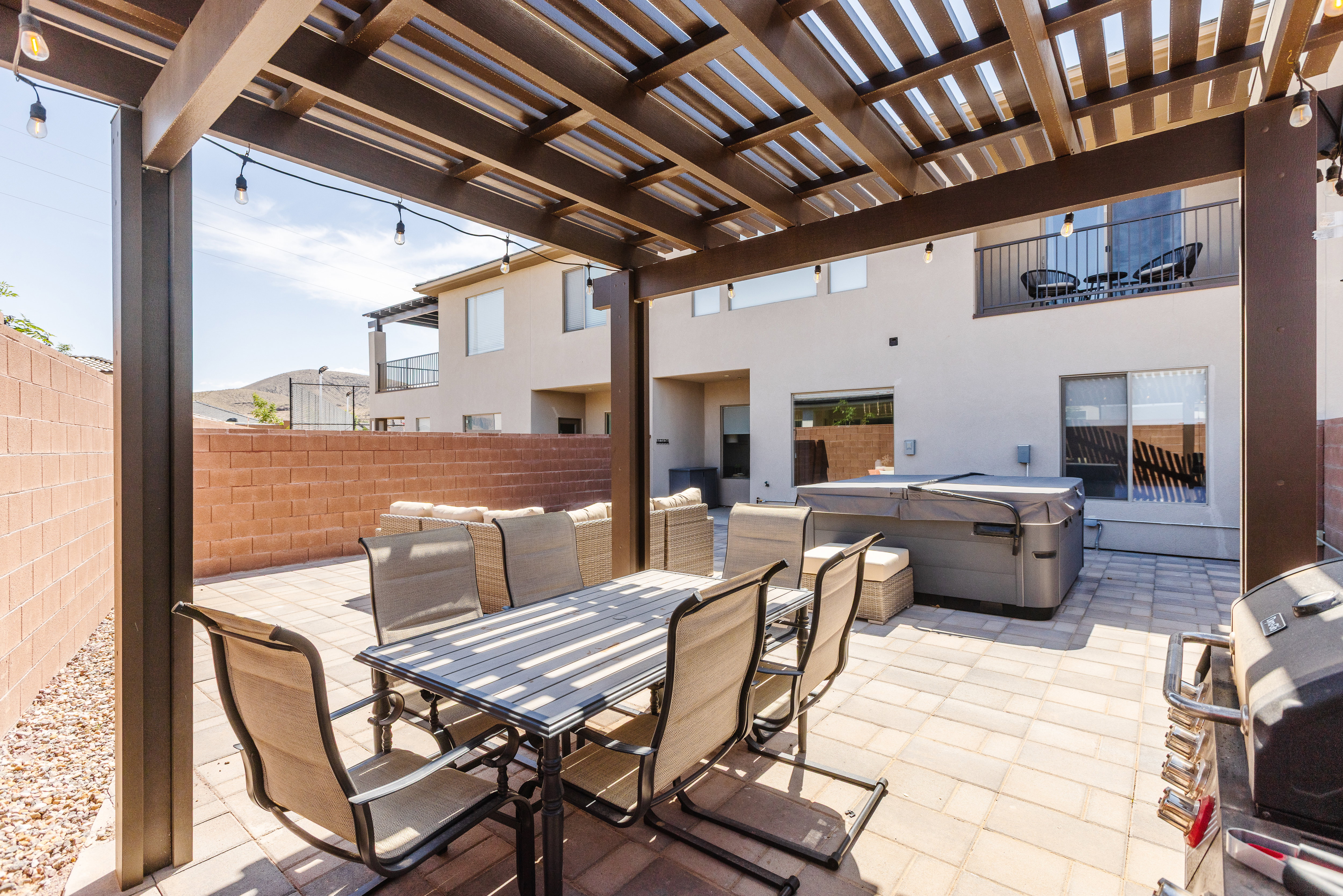 Fenced backyard featuring a hot tub, outdoor dining area, a grill, a pergola, and a patio