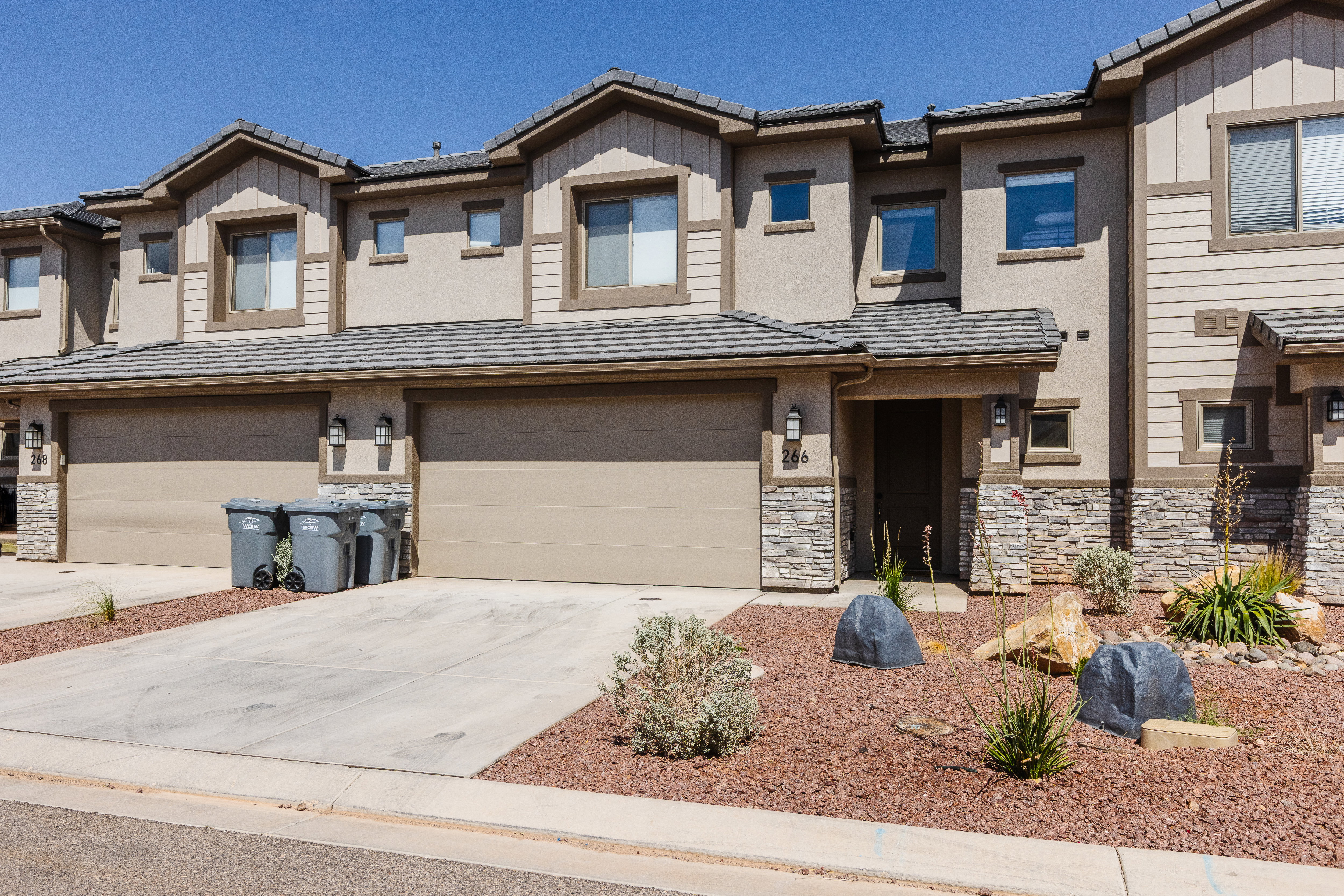 View of front of home featuring a tile roof, concrete driveway, an attached garage, and board and batten siding