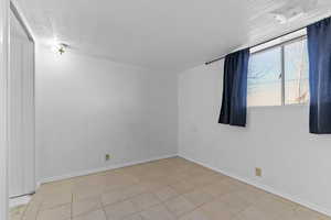 Spare room featuring a textured ceiling and light tile patterned flooring